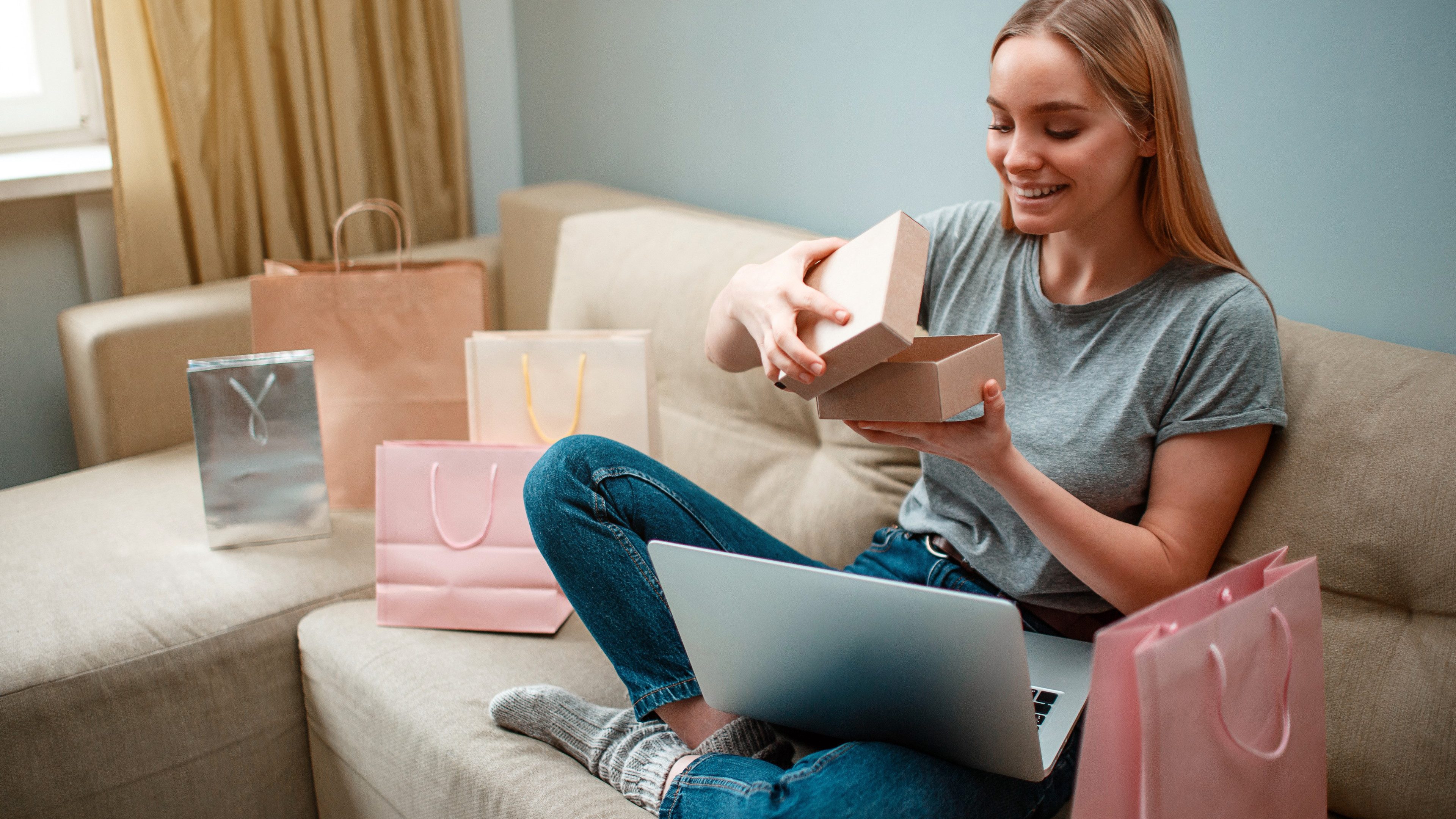 Online shopping at home. Young smiling shopper is unboxing her new parcel and looking into, ordered and delivered by internet