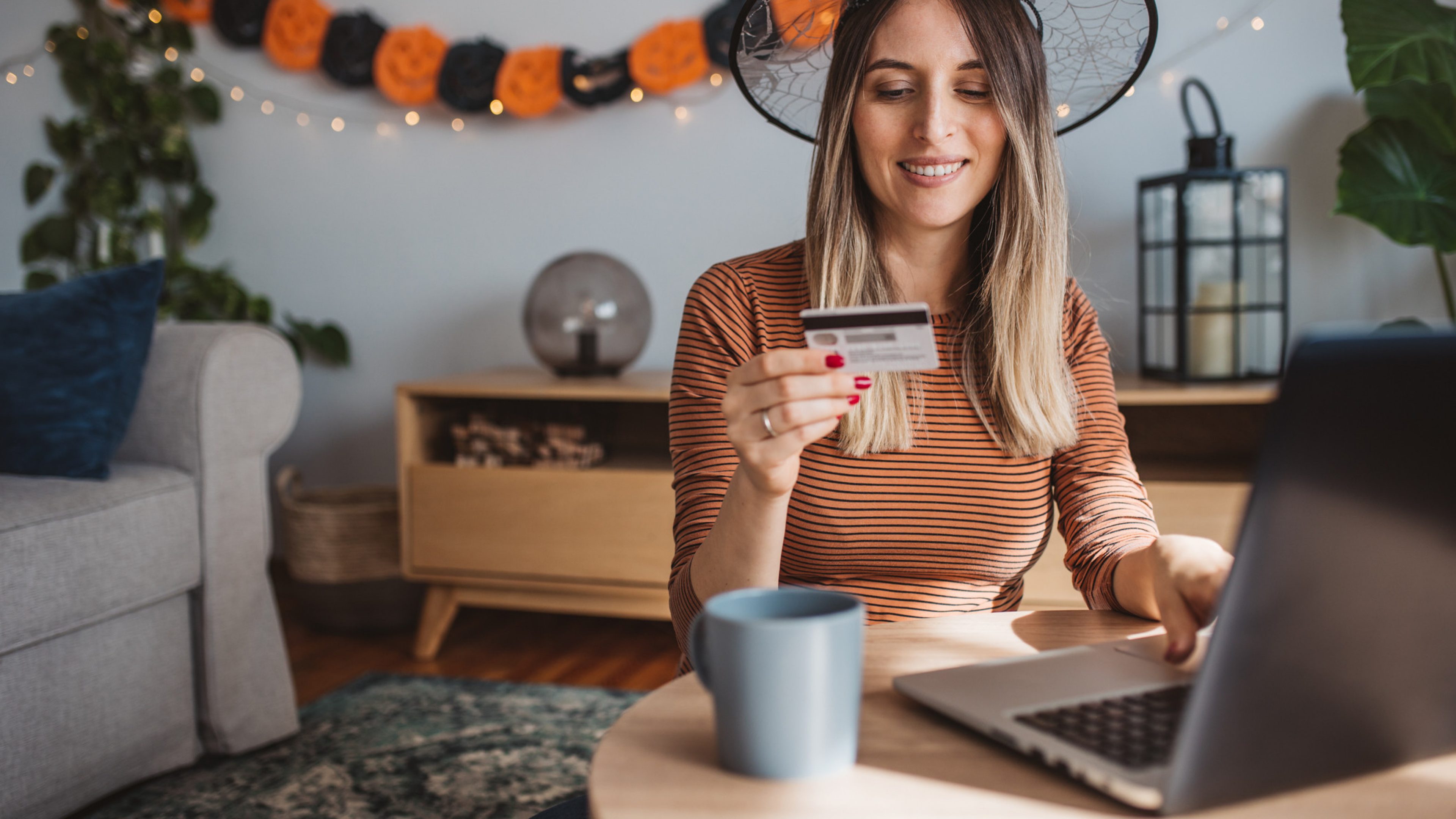 Young pregnant woman preparing for Halloween. She is decorating and shopping online.