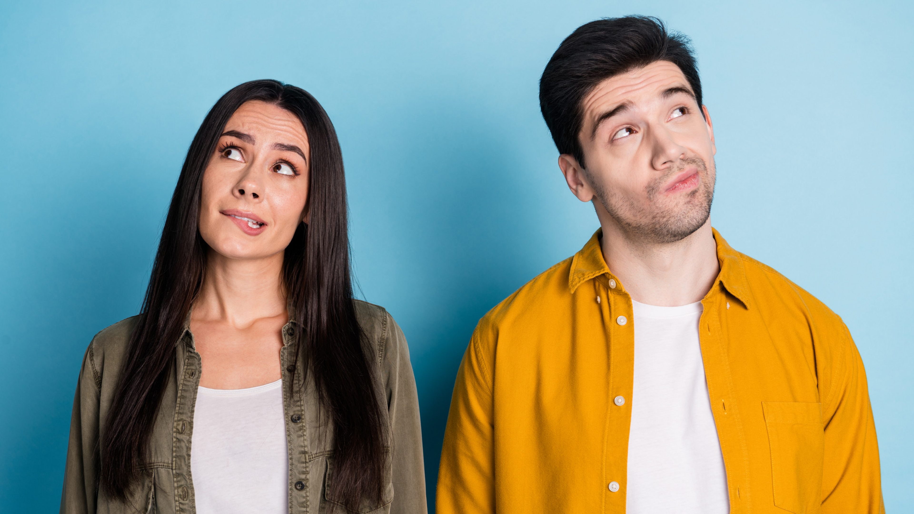 Photo of two nice young partners look empty space wear shirt isolated on blue color background.