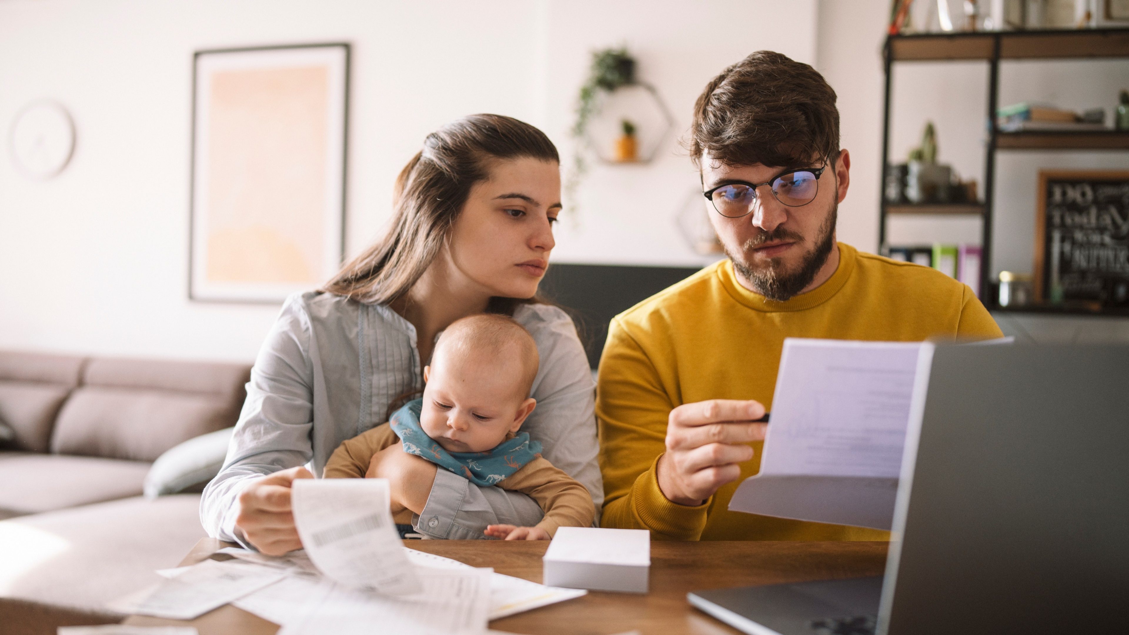 Young family with baby worried about family budget and high taxes and bills. Inflation concept.