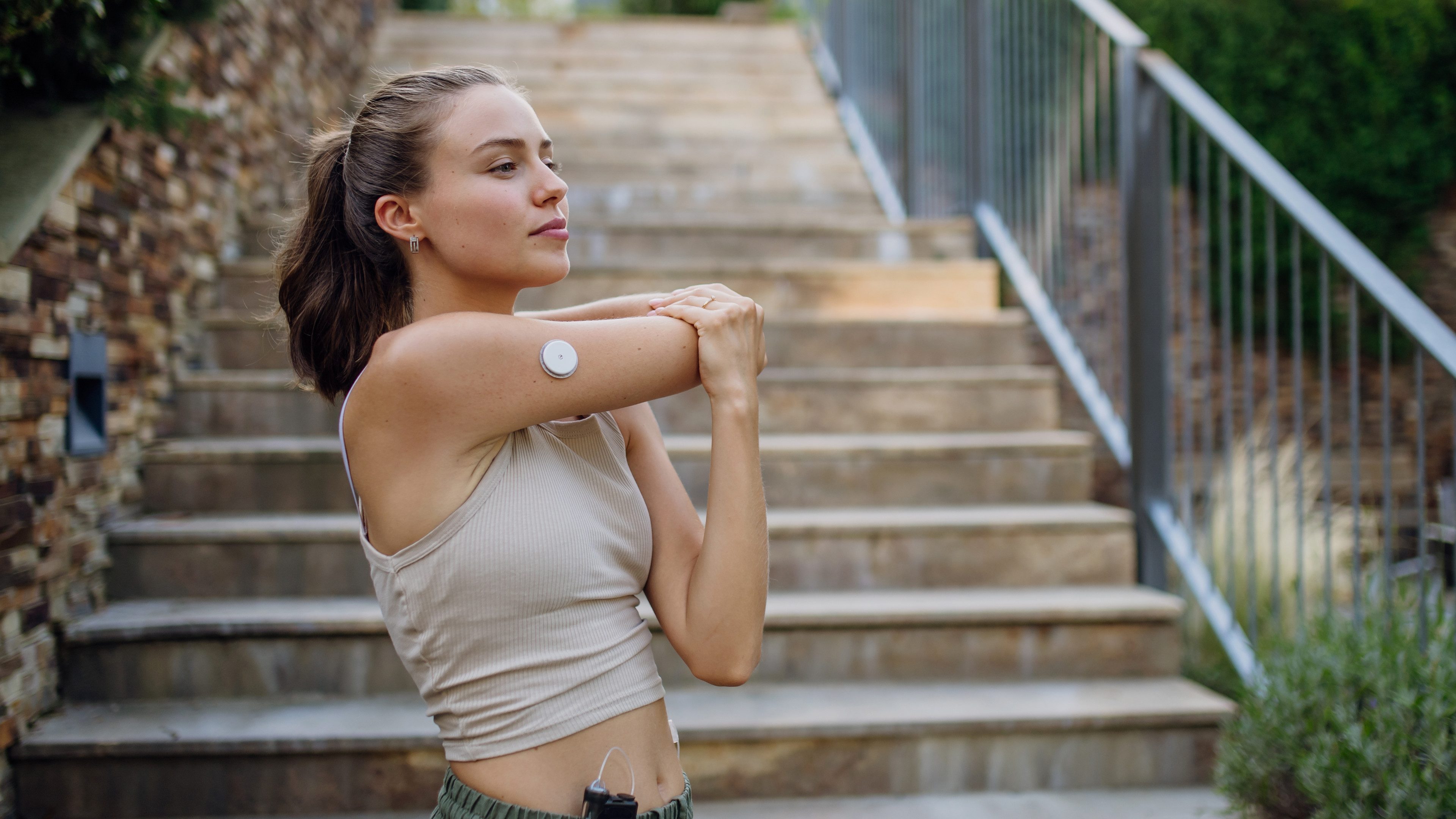 Beautiful diabetic woman preparing for outdoor run in the city. Young woman wearing an insulin pump during exercising. Concept of exercise and diabetes.