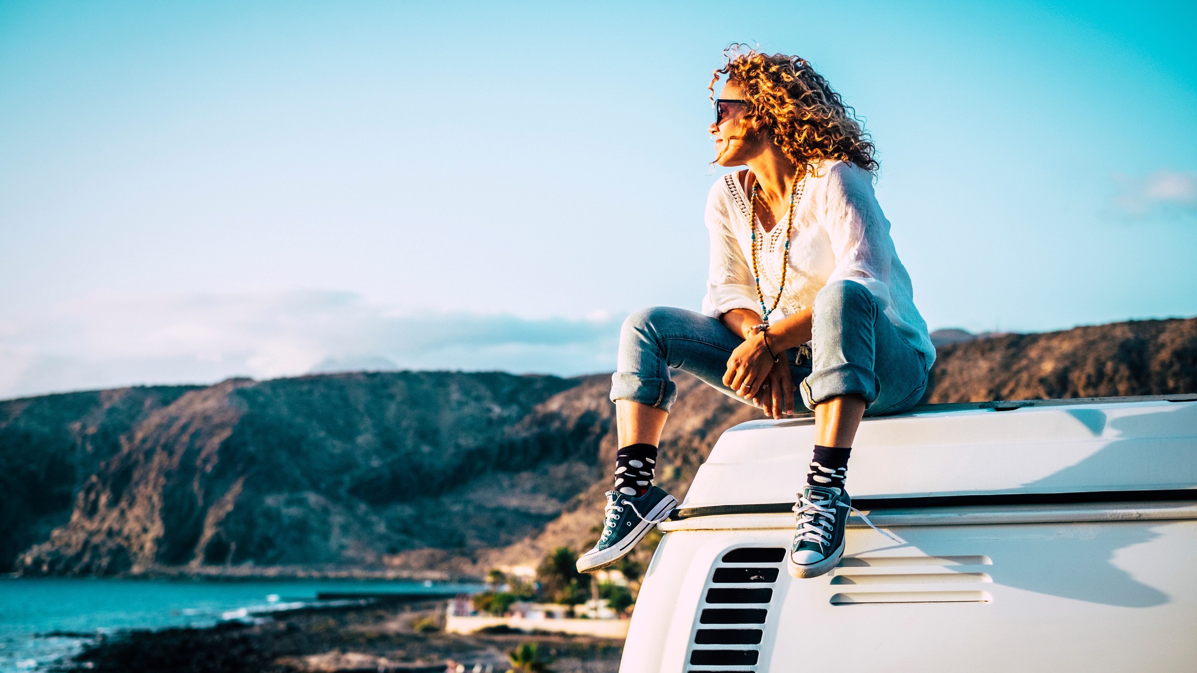 Travel concept with independent people enjoyig the outdoor leisure activity and wanderlust life lifestyle - woman sit down on the roof of a old nice vintage camper van
