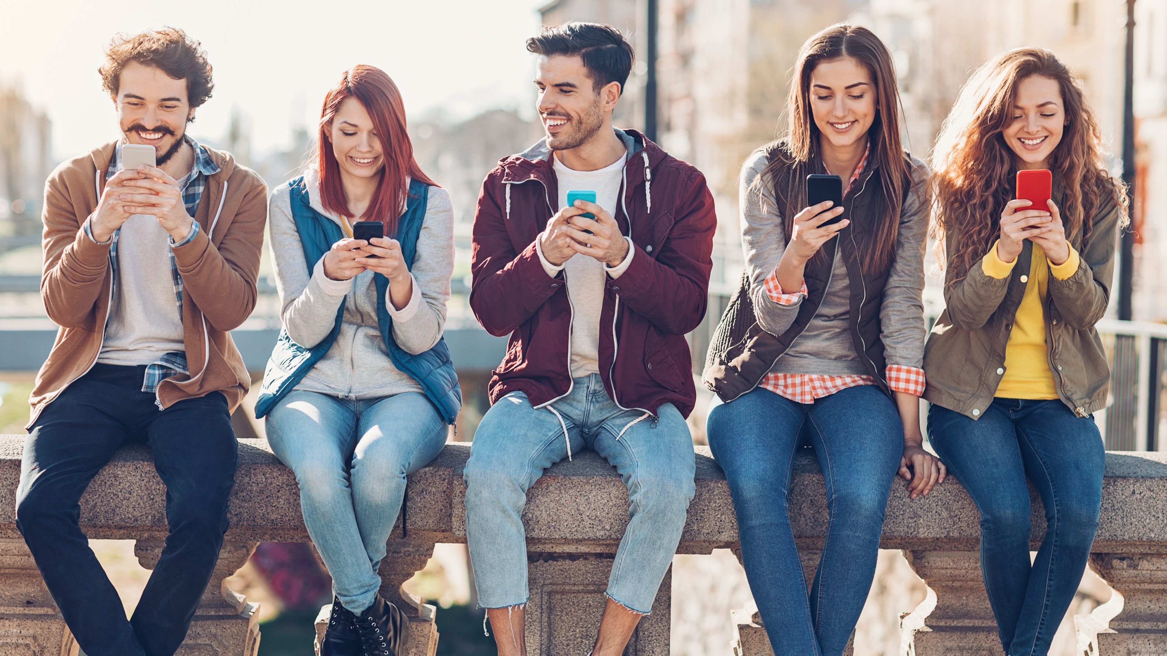 Group of young people with smart phones outdoors in the city